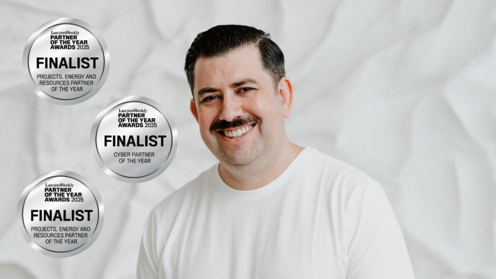 Smiling man with dark hair and mustache wearing white shirt, three award finalist badges.