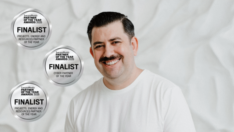 Smiling man with dark hair and mustache wearing white shirt, three award finalist badges.