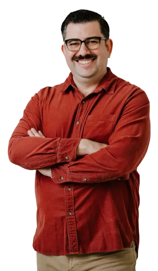 Middle-aged man with glasses and mustache wearing a red button-up shirt, smiling with arms crossed.